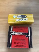 Velos 350 stapler box on top, Arrow stapler red and black box beneath on wood surface