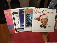 Five vintage LP albums shown standing upright, partially overlapping. Visible titles include Perry Como, Bing Crosby Merry Christmas, Christmas Memories, The Magic Organ, and Barbie Allen Dancercise.