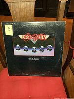 Front cover of Aerosmith 'Rocks' vinyl LP album showing logo, spheres, and wear.