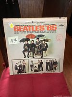 Front cover of The Beatles Beatles '65 album showing band members sitting with umbrellas. Shows wear and slight discoloration.