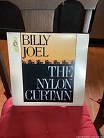 Front cover of Billy Joel The Nylon Curtain vinyl LP album showing album title and stylized house silhouettes.