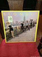 Front cover of Blondie Auto American LP showing band on rooftop with city skyline and yellow border.