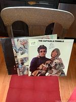 Photo showing three vinyl LP album covers: The Captain & Tennille (front), Stampeders (middle), and Diana Ross (back). The Captain & Tennille album features the duo holding bulldogs; Stampeders jacket appears damaged.