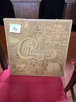 Photo of vintage Chicago VII album cover with embossed design and some visible wear on the corners.