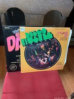 Front view of Disco Hustle double album in yellow cover with dancing people photo and pricing marks, placed in front of another black cover disco album showing the titles.