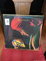Front cover of Electric Light Orchestra Discovery vintage vinyl LP showing colorful illustrated artwork with person in red headscarf looking at glowing orb logo.