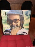 Front cover of Elton John Rock of the Westies album with a close-up photo of Elton John wearing glasses and a hat.
