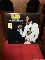 Front cover of the Elvis Presley Promised Land album showing Elvis in a white suit holding a microphone, with the album title and artist name.