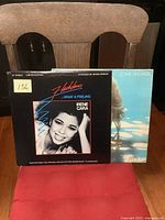 Photo showing two vinyl records, Irene Cara Flashdance 12'' single in front and partially visible Olivia Newton-John album behind