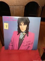 Front cover of the Joan Jett & The Blackhearts 'I Love Rock 'n Roll' album showing Joan Jett in a bright pink jacket with a blue scarf, featuring the iconic handwritten 'I Love Rock n Roll' text.
