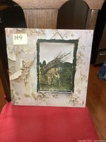 Front cover of Led Zeppelin IV album jacket with older man carrying sticks, peeling in corners and edges.