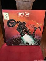 Front cover of Meatloaf Bat Out of Hell vinyl LP album showing motorcycle rider artwork with red and fiery background.