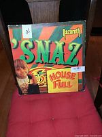 Front cover of Nazareth 'Snaz' vinyl LP album showing colorful artwork and 'House Full' sign.