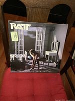 Front cover of the Ratt vinyl LP Invasion of Your Privacy album showing a woman kneeling in a room with white furniture and windows, band name and album title visible.