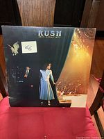 Front cover showing the vintage double LP Rush album Exit...Stage Left with performers on stage and lighting effects.