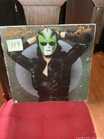 Front cover of Steve Miller Band The Joker vinyl LP featuring person in black leather jacket with horned green and white mask.