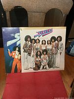 Two LP albums by The Sylvers leaning against a chair, one titled Showcase and the other partially visible titled Something Special.