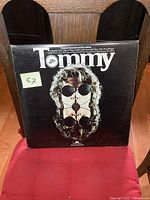Front cover of The Who Tommy vinyl double LP album showing the main face artwork with black background and the Tommy title.