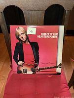 Front cover of Tom Petty and the Heartbreakers 'Damn the Torpedoes' vinyl album showing Tom Petty holding a guitar with red background.