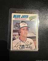 Front view of the 1977 O-Pee-Chee Doug Ault rookie baseball card in protective case showing the full card design and text.