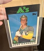 Front photo of the 1986 Topps baseball card featuring Jose Canseco in Oakland A's uniform, held in a protective plastic sleeve.