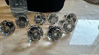 Clear oversized crystal cabinet knobs arranged on a table, showing their faceted design.