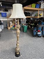 Full view of the tall floor lamp with white fabric shade in a garage setting.