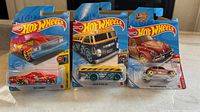 Front view of three Hot Wheels cars in blister packs showing vibrant colors and vehicle designs