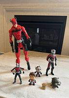 Seven Ant-Man collectibles displayed on table in front of fireplace, showing range of sizes and styles.