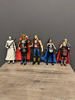 Front view of 5 Marvel Legends Thor: Love and Thunder action figures standing side by side on wood surface against grey background showing details of costumes and accessories.