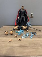 Front view of Thor figure with full accessories laid out including interchangeable heads, hands, lightning effect pieces, and Stormbreaker axe.