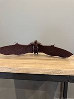 Front view of Rodan figure with fully extended wings, showing full wingspan and body detail on a wood surface.