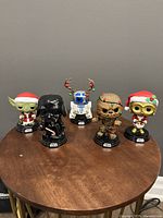 Front view of all 5 Star Wars Funko Pops with Christmas theme on a wooden table.