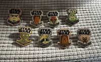 Lot of 8 Star Wars Funko enamel pins displayed on a textured surface. Characters visible include Stormtrooper, Lando Calrissian, Darth Maul, Yoda, C-3PO, Boba Fett, Chewbacca, and Tusken Raider, each with Star Wars logo above.