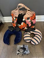 Photo showing bag, two neck pillows, included black eye masks, travel socks and earphones in plastic bag.
