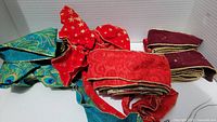 Assorted gift ribbons in various colors and patterns including teal paisley, red with stars, plain red, and burgundy with gold edging