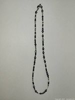 Black beaded long necklace showing dark-toned beads and silver links