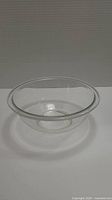 Clear glass mixing bowl shown from a side angle on white background.