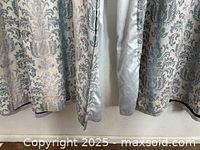 Close-up of damask curtain panels fabric and lining showing soft gray and ivory color palette and fabric texture.