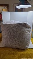 Large square floor pillow with paisley pattern in gray and white.