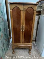 Front view of vintage oak jewelry armoire cabinet with closed doors.