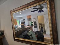 Front view of the large mirror showing its reflection of the kitchen and living space. They clearly show the rectangular shape and dual-tone frame.
