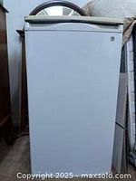 Front view of the closed white mini refrigerator showing clean exterior with a handle on top of the door.