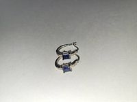 Pair of silver-tone hoop earrings with hanging square dark beads, shown on white background