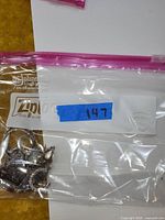 Clear plastic ziplock bag containing silver-tone jewelry pieces, showing tags and bags for storage.