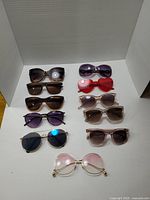 Top view of all 11 sunglasses laid out in neat rows showing various frame shapes and lens colors.