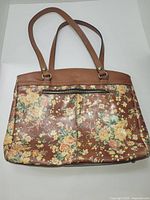 Front and side view of the vintage-style floral tote bag showing brown faux leather with floral print and double shoulder straps