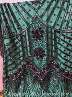 Close-up of green flapper dress fabric showing detailed black sequins and floral beading decoration