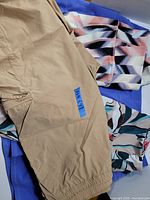 Overview of three pieces of women's athletic bottoms including beige bike shorts, geometric print capris, and floral patterned item on a blue garment.