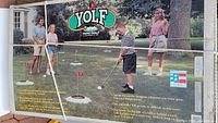 Box front with YOLF Yard Golf branding, showing people playing the game outside on grass with flags and holes.